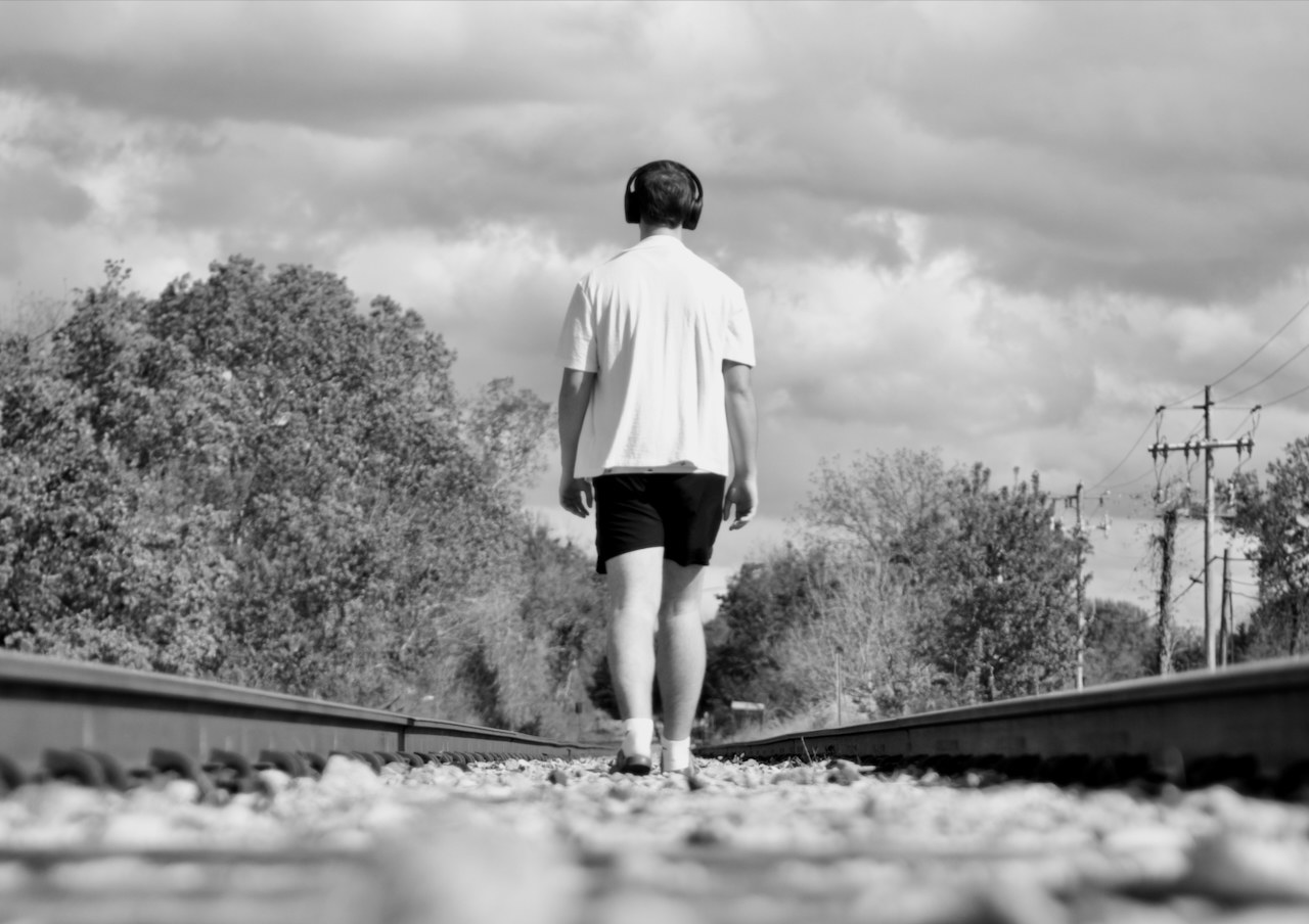 Black and white photo of Israel walking along railroad tracks